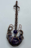 This Rock n’ Roll Lepidolite Moon Guitar Pendant is a distinctive and edgy piece of jewelry that combines the charm of lepidolite with the playful design of a guitar-shaped pendant. The pendant is crafted in copper and features an amethyst bead accent, adding a touch of elegance and color to the bold design.