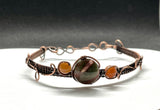 This handcrafted bracelet features a harmonious blend of earthy Rainforest Jasper and vibrant Carnelian, wrapped in warm copper wire. The adjustable design ensures a comfortable fit, while the copper wirework enhances the natural beauty of the stones.