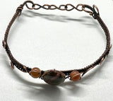 This handcrafted bracelet features a harmonious blend of earthy Rainforest Jasper and vibrant Carnelian, wrapped in warm copper wire. The adjustable design ensures a comfortable fit, while the copper wirework enhances the natural beauty of the stones.