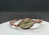 This cuff bracelet features a beautifully carved labradorite stone, known for its magical flashes of blue, green, and gold. The stone is securely wrapped in rich, handwoven copper wire, forming a bold and elegant cuff that radiates both strength and mystique.