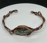 This cuff bracelet features a beautifully carved labradorite stone, known for its magical flashes of blue, green, and gold. The stone is securely wrapped in rich, handwoven copper wire, forming a bold and elegant cuff that radiates both strength and mystique.
