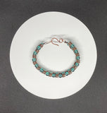 This handcrafted bracelet features rich copper wire, artistically coiled to create texture and movement, accented with vibrant teal-colored glass beads. The warm copper beautifully contrasts the cool, refreshing tones of the beads, making this piece both bold and elegant. Perfect for adding a pop of color and artisan flair to any outfit.
