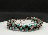 This handcrafted bracelet features rich copper wire, artistically coiled to create texture and movement, accented with vibrant teal-colored glass beads. The warm copper beautifully contrasts the cool, refreshing tones of the beads, making this piece both bold and elegant. Perfect for adding a pop of color and artisan flair to any outfit.