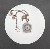 This Purple, Brown, Green, and White Stalactite Slice Necklace features a beautifully natural stalactite slice adorned with a variety of colors including purple, brown, green, and white, all set in copper. This necklace highlights the unique geological beauty of stalactites and the craftsmanship of copper jewelry.