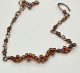 This delicate copper bracelet features an elegant wave design, accented with shimmering glass beads for a touch of color and sparkle. The bracelet is adjustable from 7 ½ to 9 inches, providing a comfortable fit, and can be shortened upon request. The warm tones of the copper combined with the playful, flowing wave design make this piece a versatile accessory for both casual and formal looks. Perfect for those who appreciate subtle elegance with a handcrafted touch.