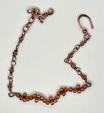 This delicate copper bracelet features an elegant wave design, accented with shimmering glass beads for a touch of color and sparkle. The bracelet is adjustable from 7 ½ to 9 inches, providing a comfortable fit, and can be shortened upon request. The warm tones of the copper combined with the playful, flowing wave design make this piece a versatile accessory for both casual and formal looks. Perfect for those who appreciate subtle elegance with a handcrafted touch.