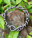 Crafted from over 6 feet of heavy-duty 8-gauge antiqued aluminum wire, this bold bangle bracelet features an intricate swirl design that’s both durable and lightweight. The antiqued finish adds depth and character.