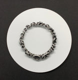 Crafted from over 6 feet of heavy-duty 8-gauge antiqued aluminum wire, this bold bangle bracelet features an intricate swirl design that’s both durable and lightweight. The antiqued finish adds depth and character.
