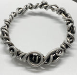 Crafted from over 6 feet of heavy-duty 8-gauge antiqued aluminum wire, this bold bangle bracelet features an intricate swirl design that’s both durable and lightweight. The antiqued finish adds depth and character.