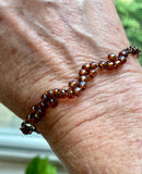 This delicate copper bracelet features an elegant wave design, accented with shimmering glass beads for a touch of color and sparkle. The bracelet is adjustable from 7 ½ to 9 inches, providing a comfortable fit, and can be shortened upon request. The warm tones of the copper combined with the playful, flowing wave design make this piece a versatile accessory for both casual and formal looks. Perfect for those who appreciate subtle elegance with a handcrafted touch.
