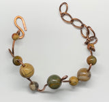 This unique bracelet is handcrafted from heavy gauge copper, shaped and curved into an organic freeform design. Accented with Picasso Jasper beads, known for their intricate natural patterns and earthy tones, The warm hues of the copper beautifully complement the stone’s striking marbled appearance. A bold statement bracelet for those who appreciate artisan craftsmanship and nature-inspired jewelry.