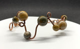 This unique bracelet is handcrafted from heavy gauge copper, shaped and curved into an organic freeform design. Accented with Picasso Jasper beads, known for their intricate natural patterns and earthy tones, The warm hues of the copper beautifully complement the stone’s striking marbled appearance. A bold statement bracelet for those who appreciate artisan craftsmanship and nature-inspired jewelry.