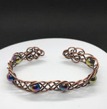 This unique 7" cuff bracelet features sturdy 18-gauge copper braided together with vibrant rainbow glass beads, creating a stunning contrast of warm metal and colorful accents. The intricate braid adds texture and depth, while the glass beads catch the light, adding a playful shimmer. Perfect for anyone who loves handcrafted, statement jewelry, this cuff is both bold and comfortable for everyday wear.