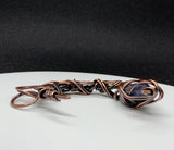 This Heavy Gauge Hammered Copper Moon Pendant is a handcrafted statement piece that features a rugged, organic design. The pendant is shaped into a crescent moon from heavy gauge copper, which has been hammered to create texture and depth. Adorning the moon are intricate copper swirls, adding a delicate touch to the bold copper design. The pendant is further enhanced by a Raw Tanzanite accent stone, which brings a pop of vibrant blue-violet color and metaphysical significance to the piece.