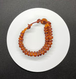 This adjustable bracelet features Vintage Glass African Trade Beads, Silk and Leather with a button closure.
