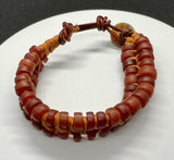 This adjustable bracelet is a stunning blend of vintage charm and contemporary craftsmanship. Featuring African trade beads, silk, and leather, this bracelet brings a touch of history and artistry to your wrist. The button closure ensures a secure fit and adds to the bracelet's unique design.