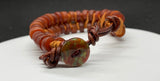 This adjustable bracelet is a stunning blend of vintage charm and contemporary craftsmanship. Featuring African trade beads, silk, and leather, this bracelet brings a touch of history and artistry to your wrist. The button closure ensures a secure fit and adds to the bracelet's unique design.