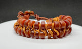 This adjustable bracelet is a stunning blend of vintage charm and contemporary craftsmanship. Featuring African trade beads, silk, and leather, this bracelet brings a touch of history and artistry to your wrist. The button closure ensures a secure fit and adds to the bracelet's unique design.