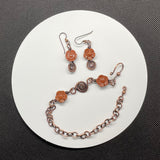 This enchanting set includes beautifully crafted earrings featuring Goldstone flowers paired with durable niobium ear wires for added comfort and style. The earrings are complemented by an adjustable bracelet, also adorned with Goldstone flowers and copper accents, ensuring a perfect fit for any wrist size. The warm, shimmering tones of Goldstone combined with the rustic charm of copper create a harmonious and eye-catching design.