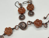 This enchanting set includes beautifully crafted earrings featuring Goldstone flowers paired with durable niobium ear wires for added comfort and style. The earrings are complemented by an adjustable bracelet, also adorned with Goldstone flowers and copper accents, ensuring a perfect fit for any wrist size. The warm, shimmering tones of Goldstone combined with the rustic charm of copper create a harmonious and eye-catching design.