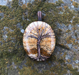 Embrace the natural beauty of the earth with the Picture Jasper Tree of Life Pendant in Copper. This stunning piece features a richly detailed picture jasper cabochon, intricately set within a handcrafted copper Tree of Life design. The pendant combines natural artistry with elegant craftsmanship, creating a timeless accessory.