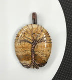 Embrace the natural beauty of the earth with the Picture Jasper Tree of Life Pendant in Copper. This stunning piece features a richly detailed picture jasper cabochon, intricately set within a handcrafted copper Tree of Life design. The pendant combines natural artistry with elegant craftsmanship, creating a timeless accessory.