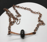 This earthy necklace features a naturally tumbled black river rock, carefully drilled and set in a heavy gauge, hammered copper mounting. The raw textures and grounding tones of the stone are beautifully contrasted by the rich, rustic warmth of the copper. A tribute to nature’s simplicity and strength—perfect for those who appreciate organic, one-of-a-kind design with a touch of rugged charm.