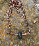 This earthy necklace features a naturally tumbled black river rock, carefully drilled and set in a heavy gauge, hammered copper mounting. The raw textures and grounding tones of the stone are beautifully contrasted by the rich, rustic warmth of the copper. A tribute to nature’s simplicity and strength—perfect for those who appreciate organic, one-of-a-kind design with a touch of rugged charm.
