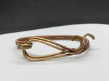 This standout bracelet features hammered brass waves, interwoven with intricate handwoven copper detailing. The combination of textures and warm metallic tones creates a unique and eye-catching piece that exudes both elegance and craftsmanship. Perfect for those who love bold, artisanal jewelry, this bracelet adds a touch of sophistication to any look.