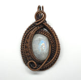 This pendant features layers of intricately wire wrapped copper surrounding an iridescent rainbow moonstone. The combination of detailed copper wirework and the moonstone’s enchanting play of colors creates a visually stunning and sophisticated piece of jewelry.