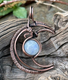 Embrace celestial elegance with the Wire Wrapped Copper Moon Pendant featuring Rainbow Moonstone. This enchanting pendant showcases a captivating blend of wire artistry and natural beauty, combining a striking copper moon design with the iridescent allure of rainbow moonstone.