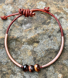 This handcrafted adjustable leather bracelet features rich faceted Tiger Eye, accented by warm copper tubes for a bold yet earthy design. The deep, chatoyant hues of the gemstone shimmer beautifully, while the supple leather ensures a comfortable fit. With its adjustable design, this bracelet is perfect for everyday wear, adding a touch of natural energy to any outfit.