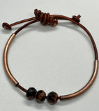 This handcrafted adjustable leather bracelet features rich faceted Tiger Eye, accented by warm copper tubes for a bold yet earthy design. The deep, chatoyant hues of the gemstone shimmer beautifully, while the supple leather ensures a comfortable fit. With its adjustable design, this bracelet is perfect for everyday wear, adding a touch of natural energy to any outfit.