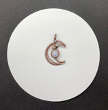 Embrace celestial elegance with the Wire Wrapped Copper Moon Pendant featuring Rainbow Moonstone. This enchanting pendant showcases a captivating blend of wire artistry and natural beauty, combining a striking copper moon design with the iridescent allure of rainbow moonstone.