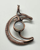 Embrace celestial elegance with the Wire Wrapped Copper Moon Pendant featuring Rainbow Moonstone. This enchanting pendant showcases a captivating blend of wire artistry and natural beauty, combining a striking copper moon design with the iridescent allure of rainbow moonstone.