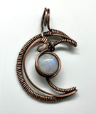 Embrace celestial elegance with the Wire Wrapped Copper Moon Pendant featuring Rainbow Moonstone. This enchanting pendant showcases a captivating blend of wire artistry and natural beauty, combining a striking copper moon design with the iridescent allure of rainbow moonstone.
