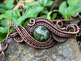 This Copper Ore Jasper Bracelet features a stunning Copper Ore Jasper stone as its focal point, surrounded by intricate, rolling hand-woven copper weaves. The bracelet combines the natural beauty of the jasper stone with the warmth and artistry of copper wirework, creating a bold and elegant accessory that showcases skilled craftsmanship. The earthy tones of the stone paired with the flowing copper design make this a striking and versatile piece.