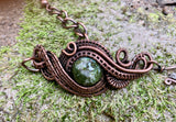 This Copper Ore Jasper Bracelet features a stunning Copper Ore Jasper stone as its focal point, surrounded by intricate, rolling hand-woven copper weaves. The bracelet combines the natural beauty of the jasper stone with the warmth and artistry of copper wirework, creating a bold and elegant accessory that showcases skilled craftsmanship. The earthy tones of the stone paired with the flowing copper design make this a striking and versatile piece.