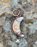 This Crazy Lace Agate Moon Pendant is a stunning piece of jewelry featuring a moon-shaped Crazy Lace Agate gemstone wrapped in copper wire with a Quartz star dangle. Known for its intricate patterns and vibrant colors, Crazy Lace Agate adds a unique and whimsical touch to this celestial-themed pendant. The addition of the Quartz star dangle enhances its charm and makes it a distinctive and elegant accessory.
