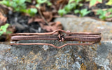 This striking bracelet showcases a harmonious blend of artisan techniques, featuring intricate woven copper, a symbolic Lover's Knot centerpiece, and hammered accents for added texture and depth. The design is completed with a secure hinged clasp, combining style and functionality. A true statement piece, this handcrafted bracelet is perfect for those who appreciate unique, skillfully made jewelry.