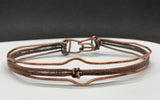 This striking bracelet showcases a harmonious blend of artisan techniques, featuring intricate woven copper, a symbolic Lover's Knot centerpiece, and hammered accents for added texture and depth. The design is completed with a secure hinged clasp, combining style and functionality. A true statement piece, this handcrafted bracelet is perfect for those who appreciate unique, skillfully made jewelry.