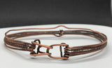 This striking bracelet showcases a harmonious blend of artisan techniques, featuring intricate woven copper, a symbolic Lover's Knot centerpiece, and hammered accents for added texture and depth. The design is completed with a secure hinged clasp, combining style and functionality. A true statement piece, this handcrafted bracelet is perfect for those who appreciate unique, skillfully made jewelry.