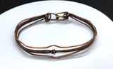 This striking bracelet showcases a harmonious blend of artisan techniques, featuring intricate woven copper, a symbolic Lover's Knot centerpiece, and hammered accents for added texture and depth. The design is completed with a secure hinged clasp, combining style and functionality. A true statement piece, this handcrafted bracelet is perfect for those who appreciate unique, skillfully made jewelry.