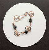 This bracelet features hand-formed and hammered copper links, each uniquely crafted for a rustic yet refined appeal. Adorned with beautiful Botswana agate beads, known for their soothing gray and earthy tones, this bracelet combines elegance with natural charm. Perfect for everyday wear or as a statement accessory.