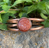 This beautiful bangle bracelet features a vibrant Carnelian stone intricately carved into a delicate flower, accentuating the stone’s natural warm hues. The flower is set on a handcrafted copper bangle, adding an earthy elegance and timeless charm. Perfect for nature lovers and those who appreciate artisanal jewelry, this bracelet makes a lovely statement piece with its warm colors and unique design.