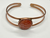This beautiful bangle bracelet features a vibrant Carnelian stone intricately carved into a delicate flower, accentuating the stone’s natural warm hues. The flower is set on a handcrafted copper bangle, adding an earthy elegance and timeless charm. Perfect for nature lovers and those who appreciate artisanal jewelry, this bracelet makes a lovely statement piece with its warm colors and unique design.