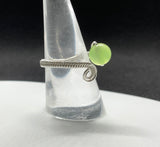 This stunning adjustable ring showcases a vibrant apple-green Prehnite gemstone, elegantly wrapped in intricate Argentium silver wire. The delicate wire weaving enhances the natural beauty and translucence of the Prehnite, creating a harmonious blend of soft green hues and shimmering silver. The adjustable band ensures a comfortable fit. A perfect piece for those who love unique, handcrafted jewelry with a pop of color!