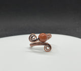 This sparkling adjustable ring features a radiant Goldstone, known for its deep coppery glow and subtle shimmer. Wire wrapped Copper and the warm tones of both stone and metal create a rich, earthy elegance. The adjustable band ensures a comfortable fit.