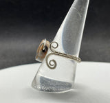 This unique ring showcases a stunning Venus Jasper gemstone, meticulously wrapped in high-quality Argentium silver wire for a sleek and contemporary design. The adjustable nature of the band allows it to fit comfortably for sizes 9 and up, making it perfect for a variety of hand sizes. Venus Jasper, known for its grounding properties and beautiful earthy tones, creates a striking contrast against the bright, tarnish-resistant Argentium silver.