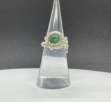 This stunning adjustable ring features a mesmerizing Green Goldstone, wire wrapped in Argentium Silver. The rich green tones of the Goldstone sparkle with flecks of silver, creating a captivating effect that catches the light beautifully. The ring's adjustable design ensures a perfect fit for various finger sizes, making it a versatile and elegant addition to any jewelry collection. The combination of the shimmering Green Goldstone and the sleek Argentium Silver creates an eye-catching piece.